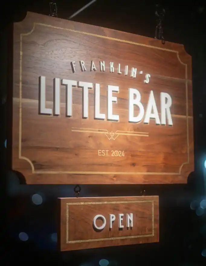 The Franklin's Little Bar hanging sign, lit up and open