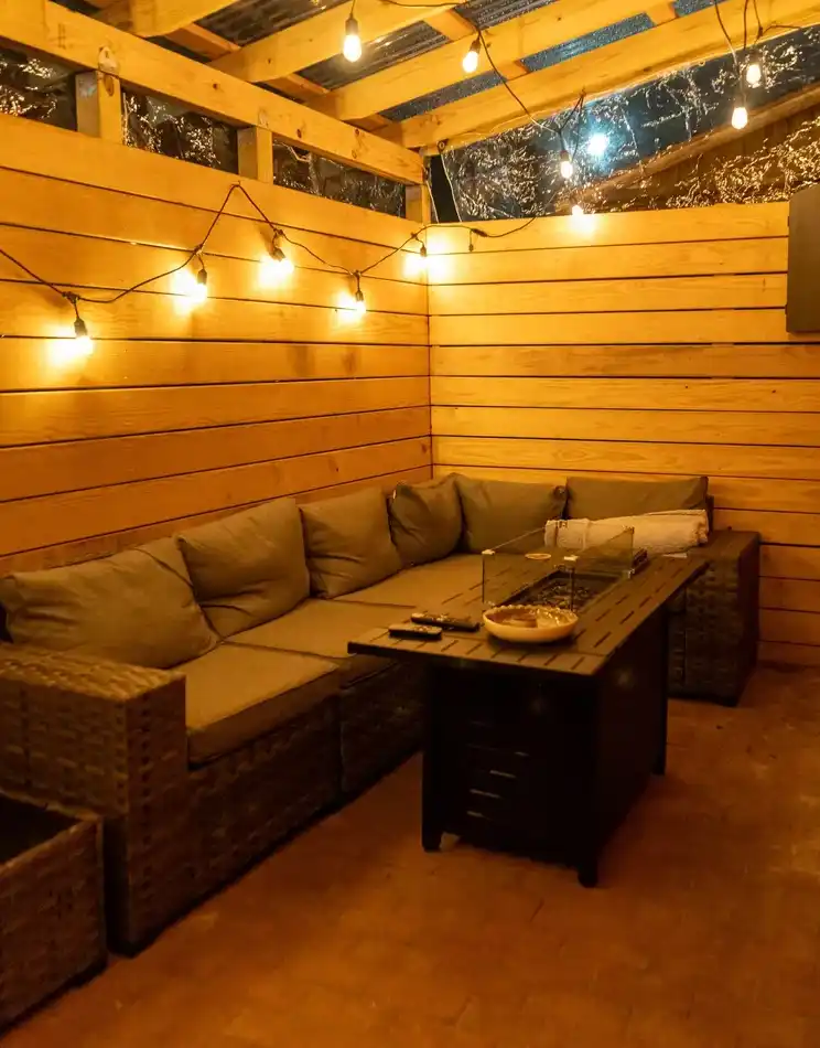 The covered patio lounge with string lights and a fire pit table